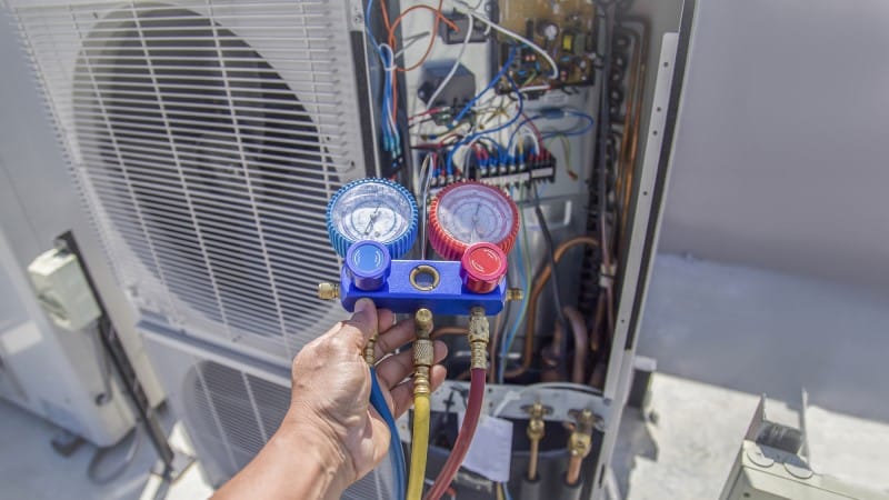 Hand of technician repairing residential air conditioning system
