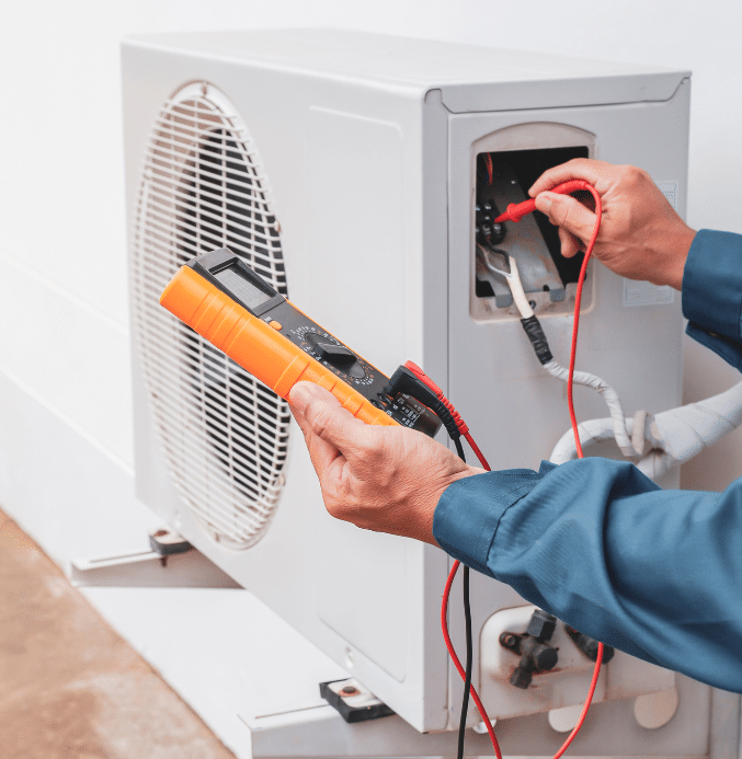 HVAC technician using a multimeter to test wiring on an outdoor air conditioning unit. AC repair and maintenance service in progress with electrical diagnostic tools.